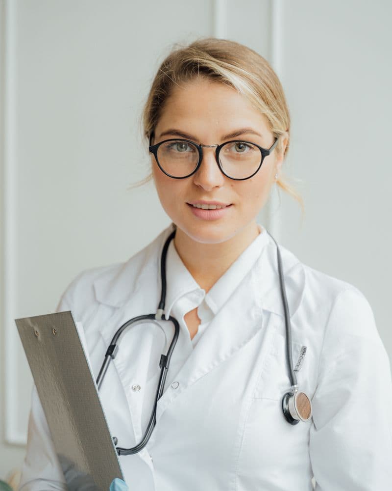Young physician in a white coat looking toward the camera